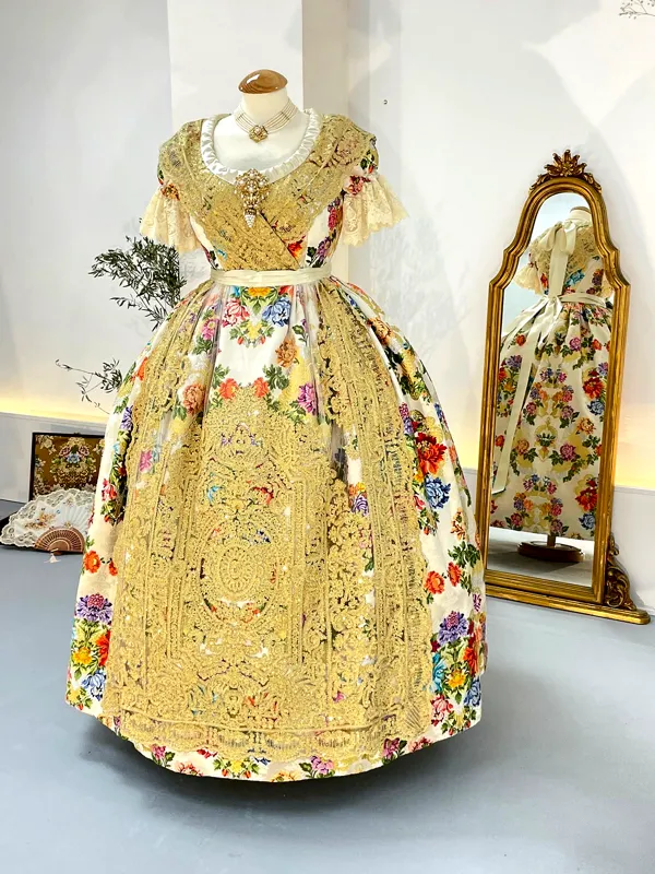 Traje de fallera blanco con delantal oscuro expuesto en un maniquí